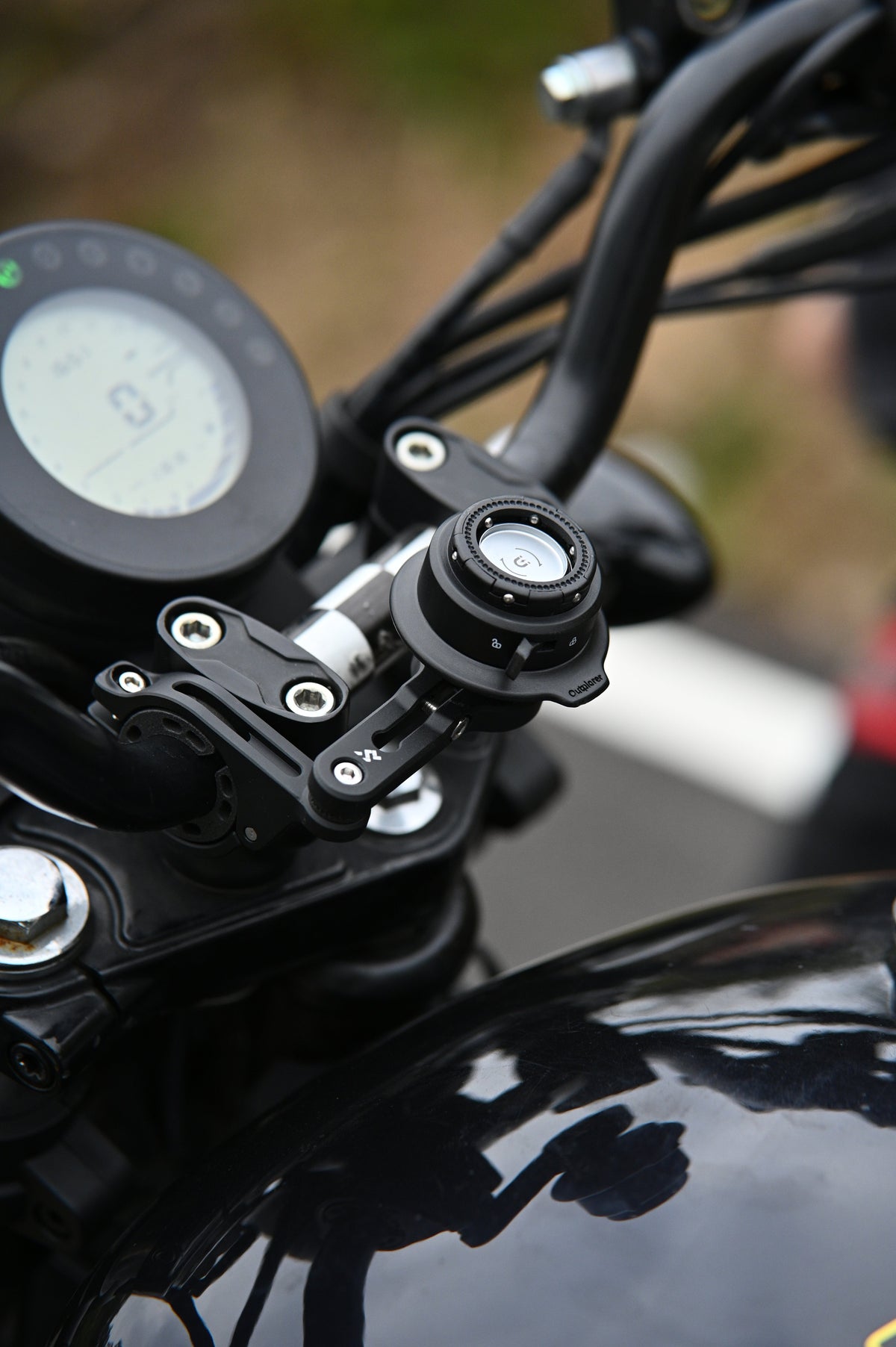 Porta cellulare Outplorer QM02 montato sul manubrio di una moto, accanto al cruscotto
