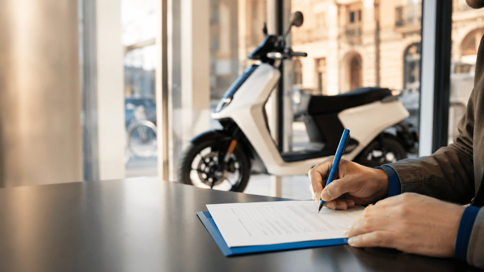 Documenti di acquisto firmati in concessionaria con scooter elettrico sullo sfondo