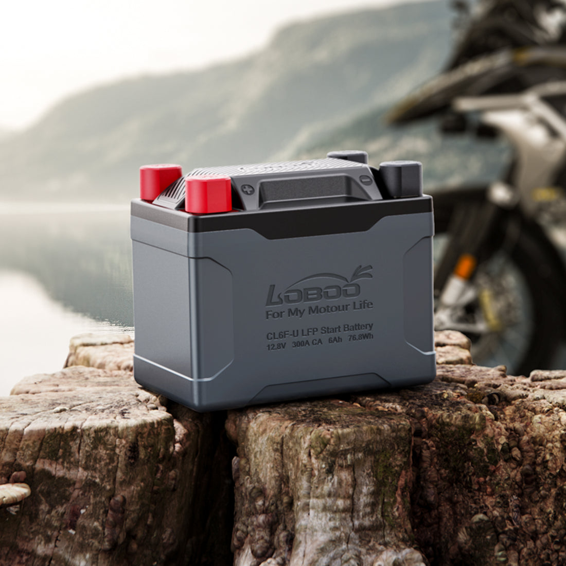 Batteria al litio LOBOO CL6F-U su un tronco, con moto adventure sullo sfondo