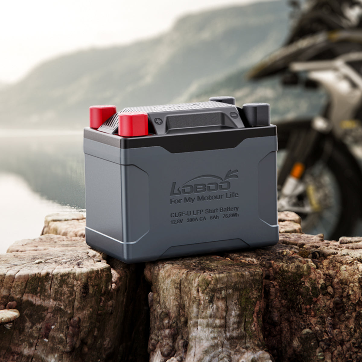 Batteria al litio LOBOO CL6F-U su un tronco, con moto adventure sullo sfondo