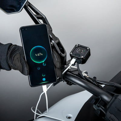 Smartphone in ricarica dal LOBOO C36 durante una sosta, comando con guanto da moto